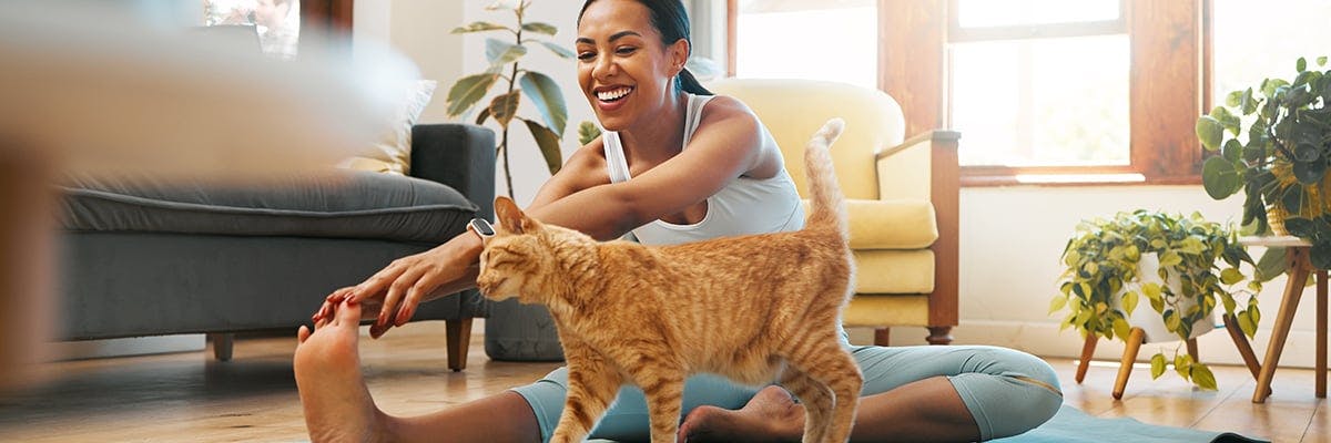 A smiling woman stretching beside her cat
