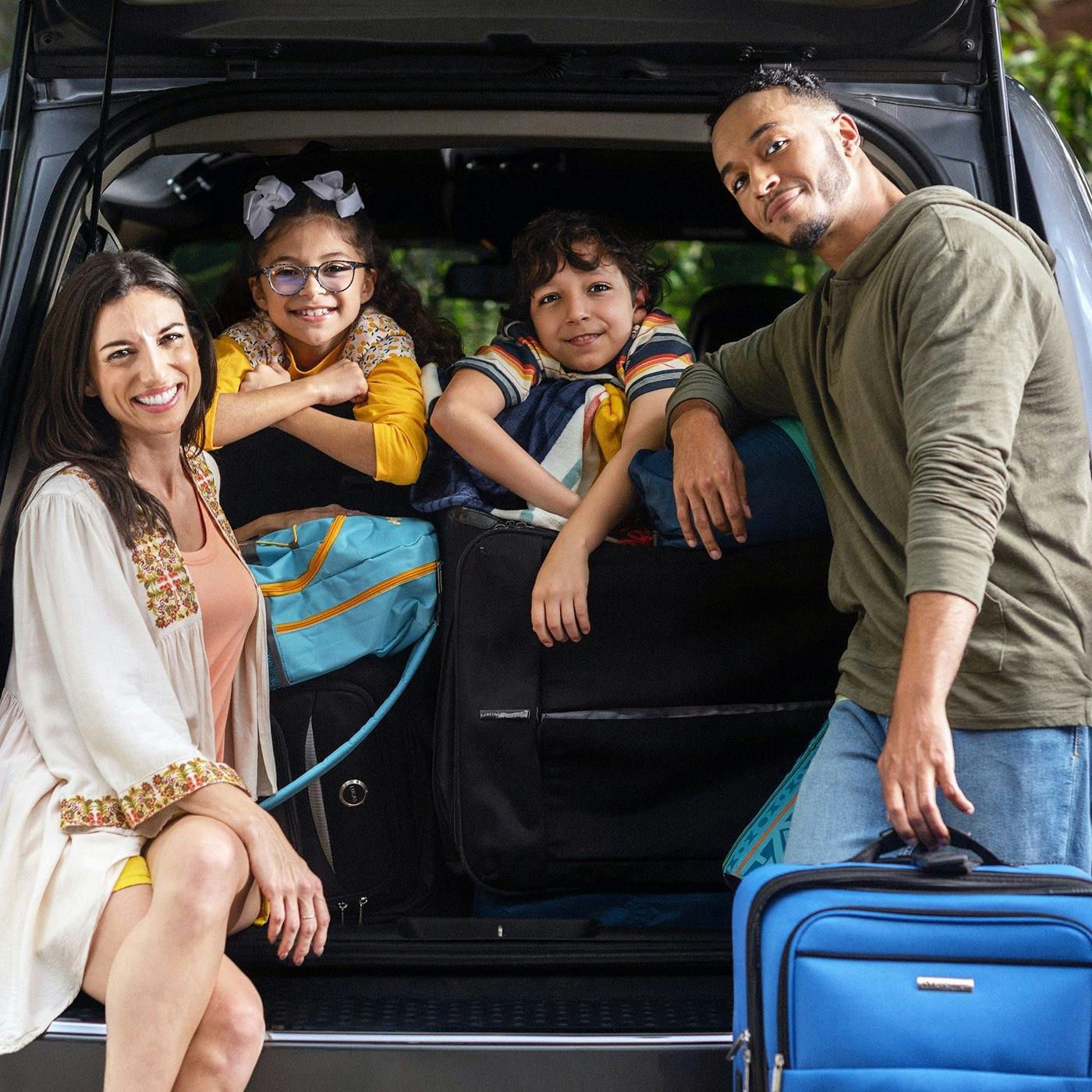 A smiling family with their car outdoors
