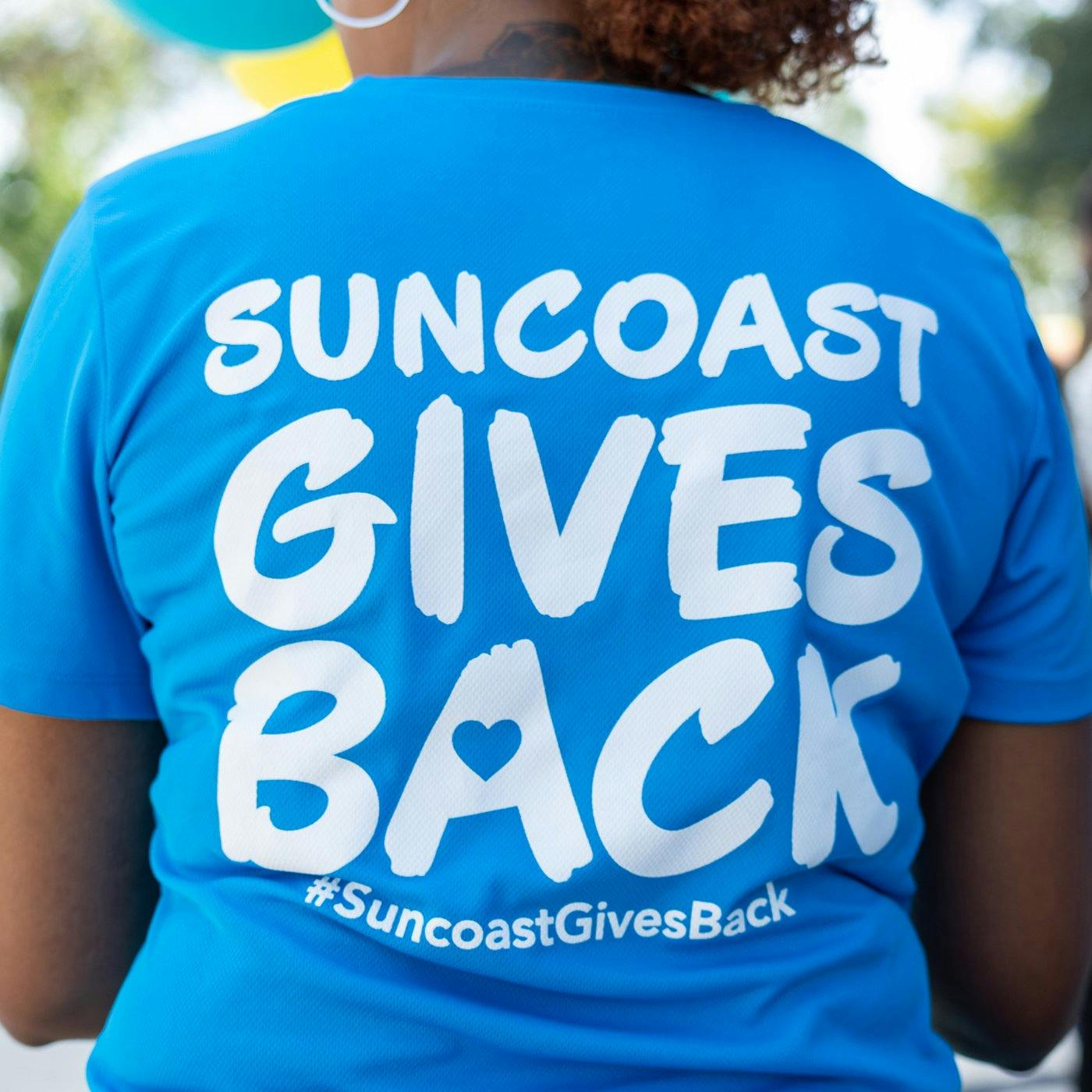 The back of a shirt that has Suncoast Gives Back printed on it