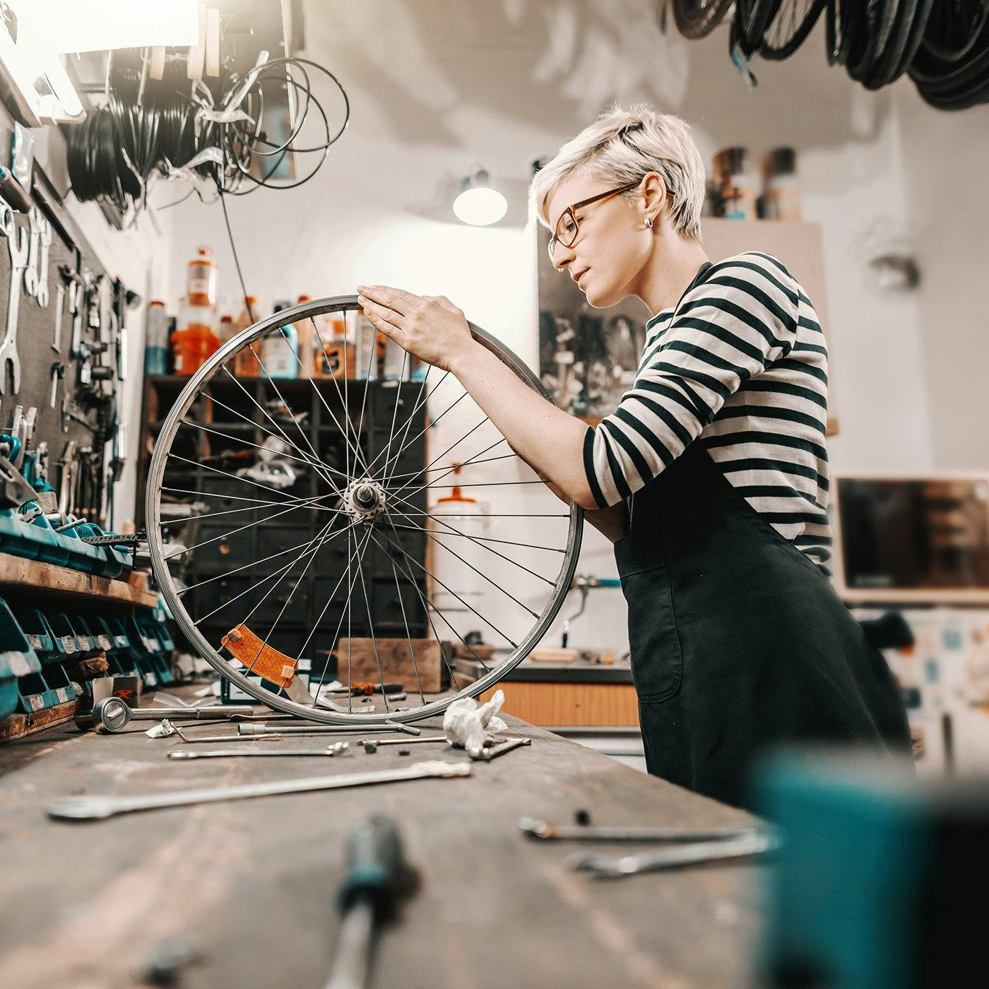 A woman working with a bicycle wheel