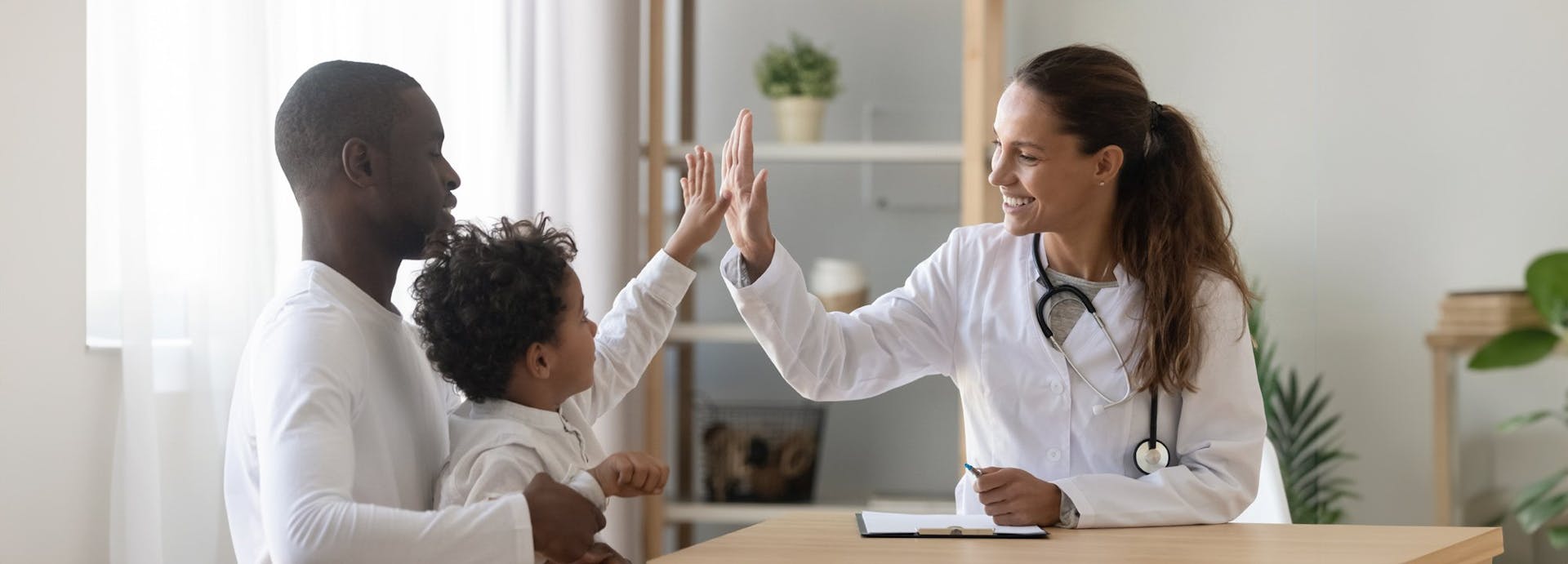 A doctor gives a high five to a boy and his father